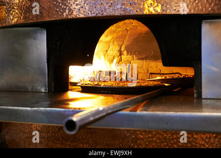 Pizzas au feu de bois traditionnels placés dans une brique chaude super four à pizza. Banque D'Images