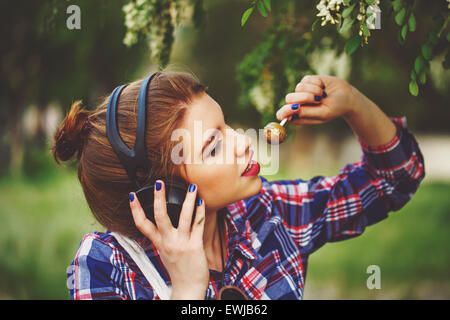 Portrait de jolie jolie jeune fille hipster des écouteurs. Fille de lécher une sucette. La tonalité chaude. Le concept de vie heureuse. Banque D'Images