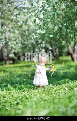 Sweet baby girl playing avec de belles fleurs Banque D'Images