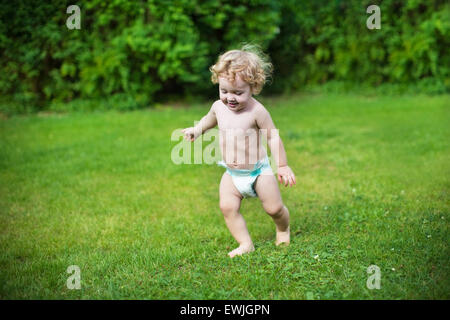 Drôle de petit bébé portant une couche d'exécution dans le jardin sur une chaude journée d'été Banque D'Images