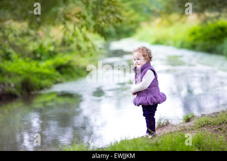 Belle petite fille marche sur une rive de la rivière sur une belle journée d'automne
