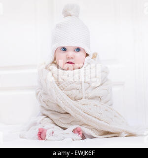 Funny cute baby avec de grands yeux bleus portant un chapeau et une énorme écharpe en tricot Banque D'Images