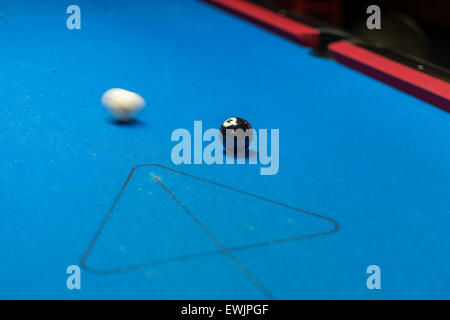 Boule blanche en mouvement sur le point de frapper la bille noire sur une table de billard Banque D'Images