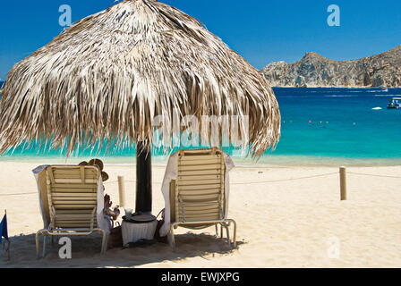 Personne assise sur chaise de plage sous palapa sur journée ensoleillée à Cabo San Lucas, Mexique. Banque D'Images