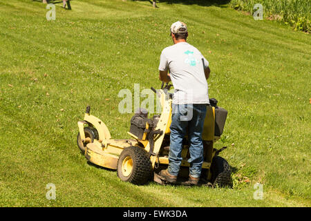 Homme debout sur le tracteur de pelouse la tonte d'une grande pelouse Banque D'Images