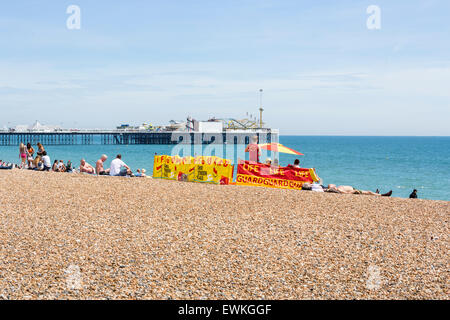 Lifeguard station sur la plage de Brighton, East Sussex, UK avec Palace Pier (jetée) derrière, un jour d'été Banque D'Images