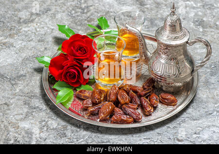 Fleurs rose rouge avec plateau et dates des fruits. Jours fériés islamiques décoration. Ramadan kareem Banque D'Images