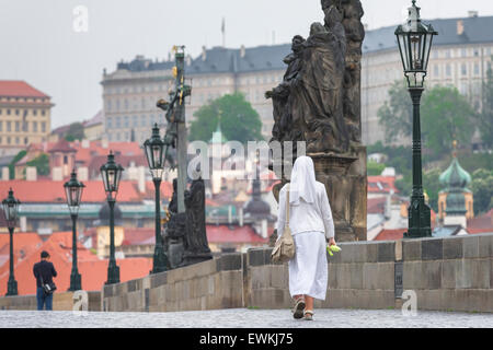 Nun de marcher seul, à l'aube d'une nonne en blanc traverse le pont Charles à Prague, République tchèque. Banque D'Images