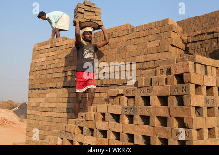 Travailleur homme transportant des briques sur sa tête à une briqueterie dans Harihar Banque D'Images