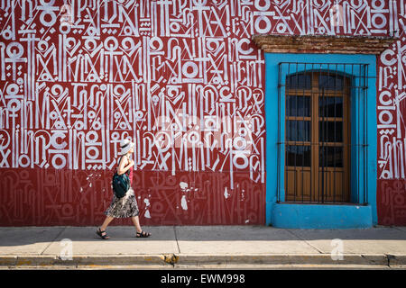 Femme marche par intéressant wall mural rempli de caractères étrangers à Oaxaca au Mexique Banque D'Images