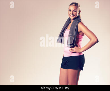 Jeune femme portant des vêtements d'entraînement posing with hand on hip and smiling at camera. Banque D'Images