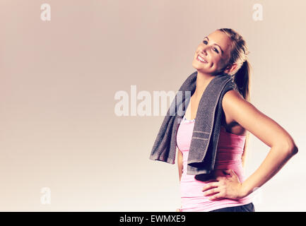 Jeune femme portant des vêtements d'entraînement avec les mains sur le houblon et la tête inclinée en arrière en souriant. Banque D'Images
