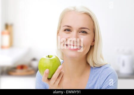 Happy woman eating apple vert sur la cuisine Banque D'Images