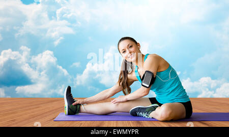 Smiling woman stretching leg sur mat sur les nuages Banque D'Images