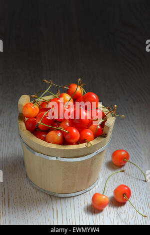 Les cerises dans un petit seau en bois Banque D'Images