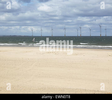 Une planche à voiles à l'avant d'un parc éolien offshore dans l'estuaire de la Rivière Tees photographiés de Redcar beach. Banque D'Images