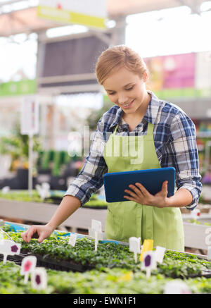 Happy woman with tablet pc in greenhouse Banque D'Images