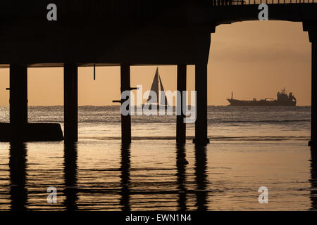 Un yacht vu à travers la silhouette de la station de sauvetage à Bembridge voile au large de la côte de l'île de Wight Banque D'Images