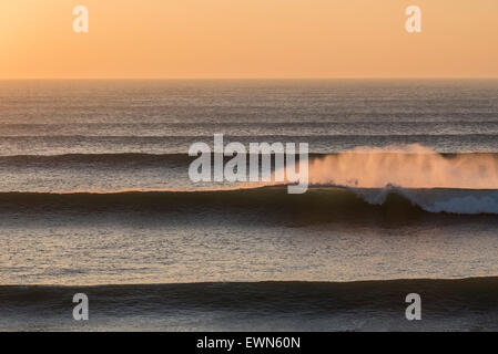 Big Spring apporte à travers les vagues de houle de l'océan Atlantique Nord à Cornwall au coucher du soleil. Banque D'Images