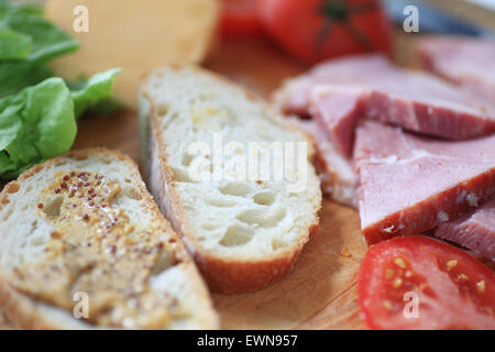 Pain de blé entier avec de la moutarde, de tranches de jambon, fromage, laitue et tomate, prêt à faire dans un repas restaurant Banque D'Images