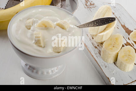 Yaourts à la banane dans un bol sur la table en bois blanc. Banque D'Images