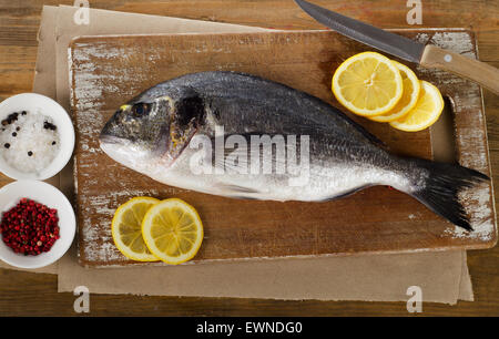 La dorade fraîche avec du citron sur une planche à découper en bois. Banque D'Images