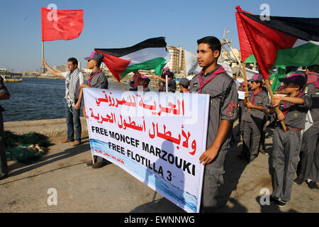 Gaza, la Palestine. 29 Juin, 2015. Les scouts palestiniens détiennent des bannières et leur drapeau national au cours d'une manifestation contre le blocage israélien d'un bateau de militants étrangers d'atteindre Gaza, au port de la ville de Gaza. © Ibrahim Khatib/Pacific Press /Alamy Live News Banque D'Images