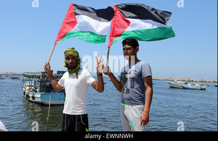 Gaza, la Palestine. 29 Juin, 2015. Palestiniens tenir drapeau national au cours d'une manifestation contre le blocage israélien d'un bateau de militants étrangers d'atteindre Gaza, au port de la ville de Gaza. © Ibrahim Khatib/Pacific Press /Alamy Live News Banque D'Images