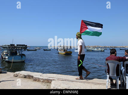 Gaza, la Palestine. 29 Juin, 2015. Un Palestinien tenir drapeau national au cours d'une manifestation contre le blocage israélien d'un bateau de militants étrangers d'atteindre Gaza, au port de la ville de Gaza. © Ibrahim Khatib/Pacific Press /Alamy Live News Banque D'Images