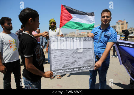 Gaza, la Palestine. 29 Juin, 2015. Tenir les Palestiniens lors d'une bannière de protestation contre le blocage israélien d'un bateau de militants étrangers d'atteindre Gaza, au port de la ville de Gaza. © Ibrahim Khatib/Pacific Press /Alamy Live News Banque D'Images