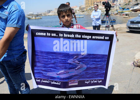 Gaza, la Palestine. 29 Juin, 2015. Un garçon palestinien détient au cours d'une bannière de protestation contre le blocage israélien d'un bateau de militants étrangers d'atteindre Gaza, au port de la ville de Gaza. © Ibrahim Khatib/Pacific Press /Alamy Live News Banque D'Images