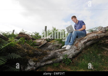 Un homme utilise une connexion internet à haut débit à l'extérieur dans un cadre rural. Banque D'Images