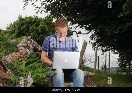 Un homme utilise une connexion internet à haut débit à l'extérieur dans un cadre rural. Banque D'Images