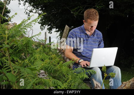 Un homme utilise une connexion internet à haut débit à l'extérieur dans un cadre rural. Banque D'Images