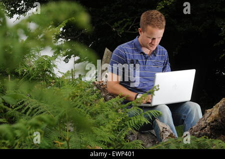 Un homme utilise une connexion internet à haut débit à l'extérieur dans un cadre rural. Banque D'Images