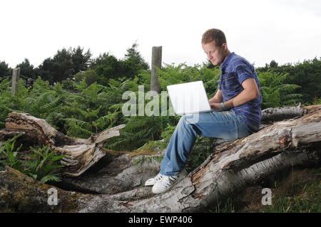 Un homme utilise une connexion internet à haut débit à l'extérieur dans un cadre rural. Banque D'Images