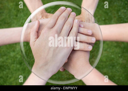 Les mains au-dessus de l'herbe se joindre à unir dans la sphère de verre Banque D'Images