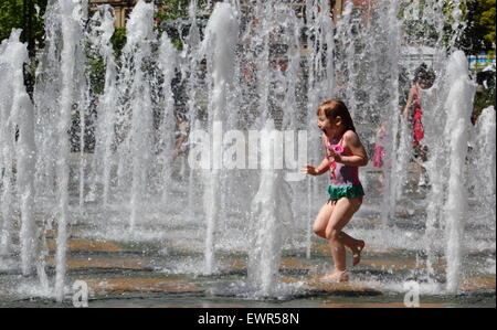 Sheffield, South Yorkshire, UK. 30 juin 2015. Une fille dans l'eau refroidit des jets d'une fontaine publique à Sheffield's Peace Gardens par temps chaud. Credit : Deborah Vernon/Alamy Live News Banque D'Images