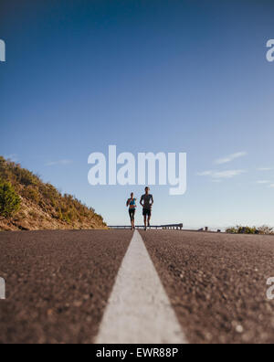 Low angle shot de deux jeunes coureurs formation ensemble sur la route. Jogging sur routes de campagne, un jour d'été avec beaucoup de copie Banque D'Images