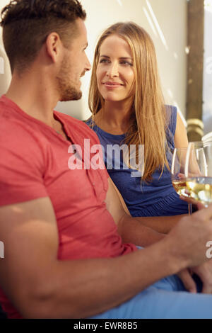 Jeune couple amour tenant un verre de vin, se regardant romantiquement. Banque D'Images