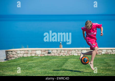 Un jeune garçon joue au football sur vacances, freestyling et astuces jouer au football dans le soleil d'été Banque D'Images