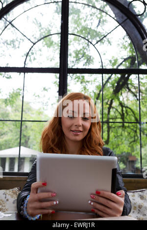 Pretty girl posing with a tablet in cafe Banque D'Images