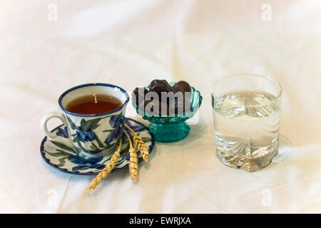 L'iftar verre d'eau et noir dates et tasse de thé Banque D'Images