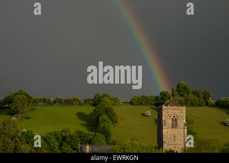 Et arc-en-ciel ciel noir,au cours d'une forte pluie douche au-dessus de l'église St Mary, dans la ville de Llanfair Caereinion Powys, Pays de Galles, Royaume-Uni, Banque D'Images