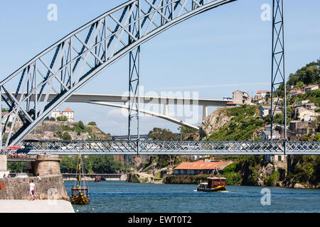 Pont Dom Luis I, dont au niveau supérieur est à la fois une passerelle et une ligne de métro et des voitures sur le niveau inférieur, de Ribeira, sur la rive nord de la rivière Douro. Les chalands amarrés ont des anciens tonneaux de vin de Porto. Porto, Portugal. Banque D'Images