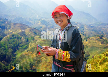 Fille Hmong tour guide sur son téléphone cellulaire à Sapa, Vietnam au-dessus de riz paddy. Banque D'Images