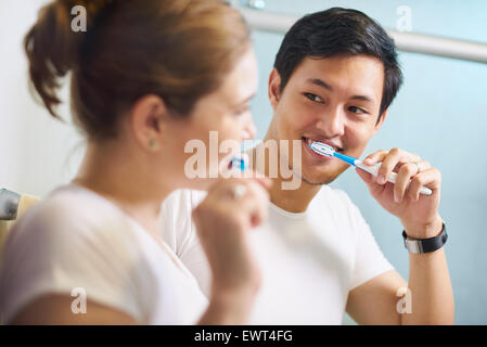 Jeune couple vivant ensemble, lave les dents dans la salle de bain le matin. La femme a l'air joyeusement à son petit ami. Concept de nouvelle Banque D'Images