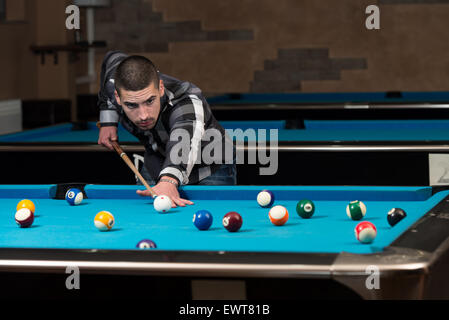 Jeune homme doublure pour balle frappée sur Table de billard Banque D'Images