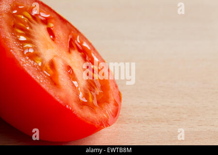 La moitié d'une tomate mûre rouge sur une planche en bois Banque D'Images