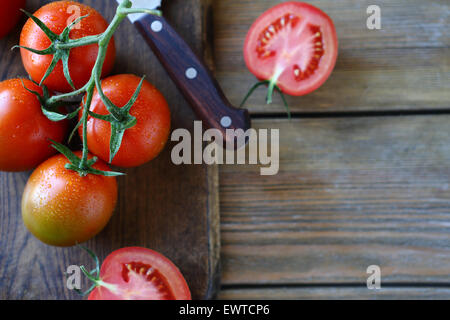 Branche de tomates rouges sur des planches, nourriture rustique Banque D'Images